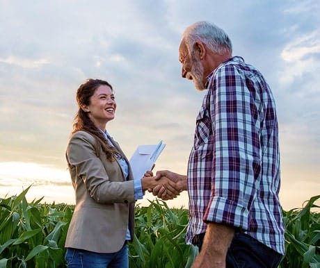 Land agent shaking hands with a farmer in a field, finalizing a land agreement